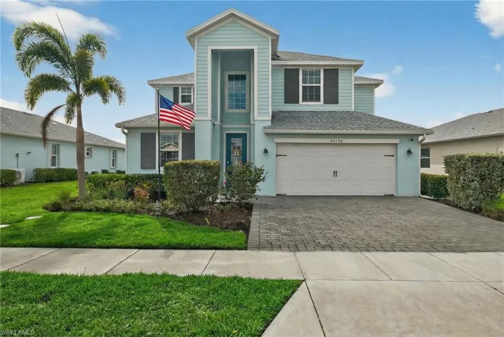 View of front of home with a garage, roof with shingles, driveway, a front yard, and stucco siding