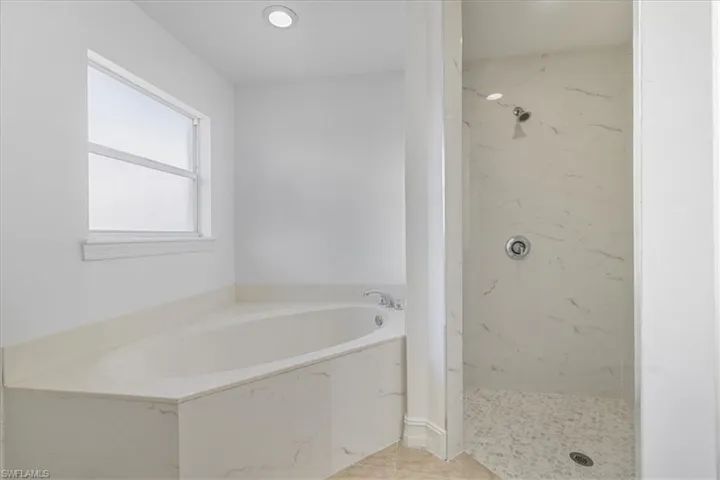 Full bath featuring a bath, a marble finish shower, and tile patterned flooring