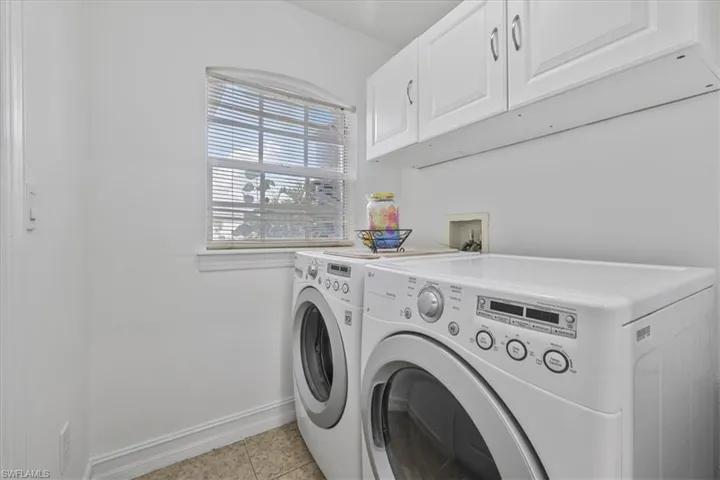 Laundry room with washer and clothes dryer, cabinet space, and light tile patterned floors