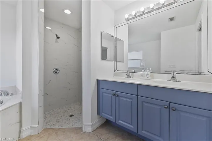 Full bath featuring double vanity, a garden tub, a marble finish shower, and tile patterned flooring