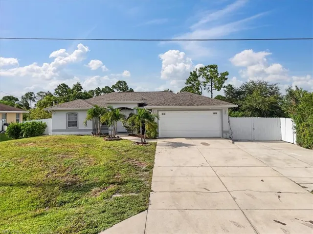 Ranch-style home with an attached garage, a gate, concrete driveway, and stucco siding