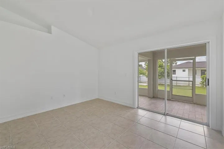 Unfurnished room with lofted ceiling and light tile patterned flooring