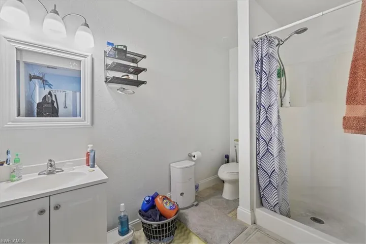 Full bathroom with vanity, a shower with curtain, a textured wall, and tile patterned flooring