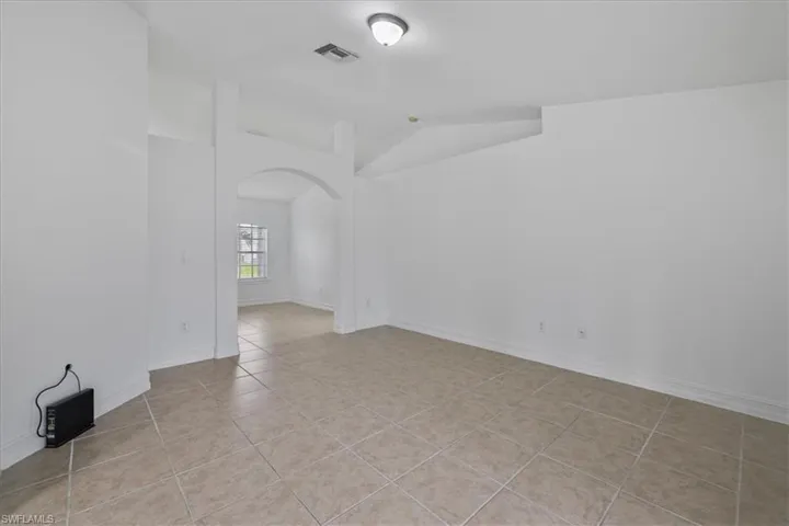 Spare room with lofted ceiling, arched walkways, and light tile patterned floors