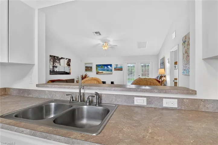 Kitchen with ceiling fan, open floor plan, light countertops, french doors, and white cabinetry
