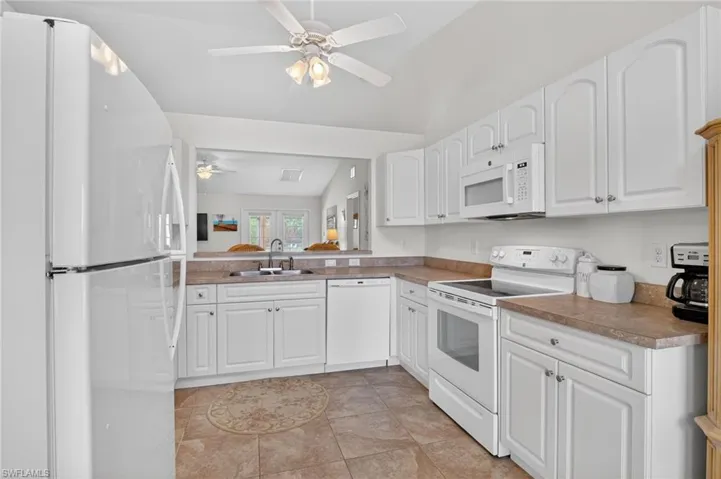Kitchen featuring white appliances, white cabinets, and ceiling fan