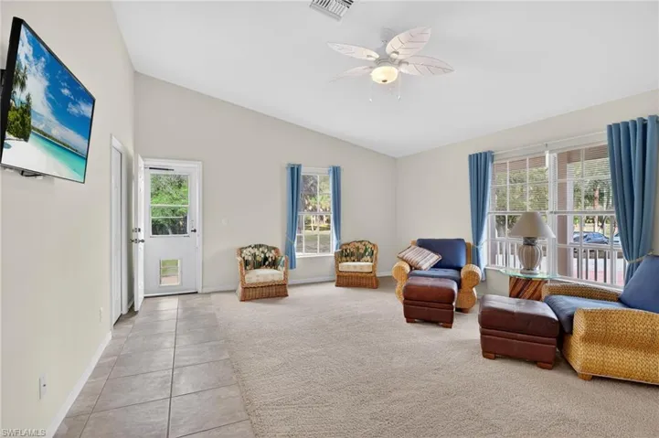 Sitting room featuring a ceiling fan, light colored carpet, light tile patterned floors, and lofted ceiling