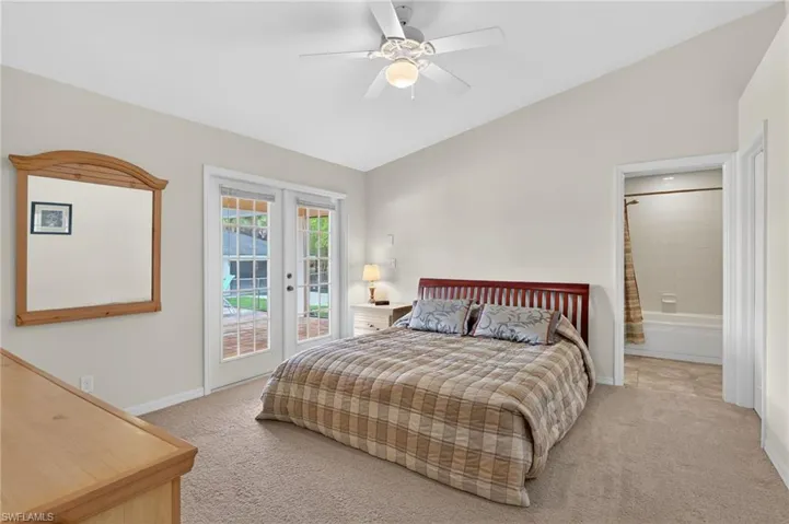 Bedroom featuring vaulted ceiling, access to exterior, light colored carpet, ceiling fan, and french doors