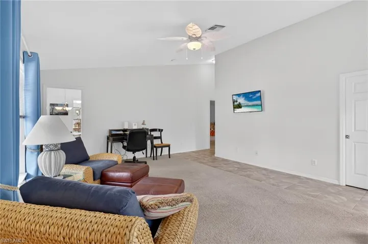 Carpeted living room featuring lofted ceiling, an office area, and ceiling fan