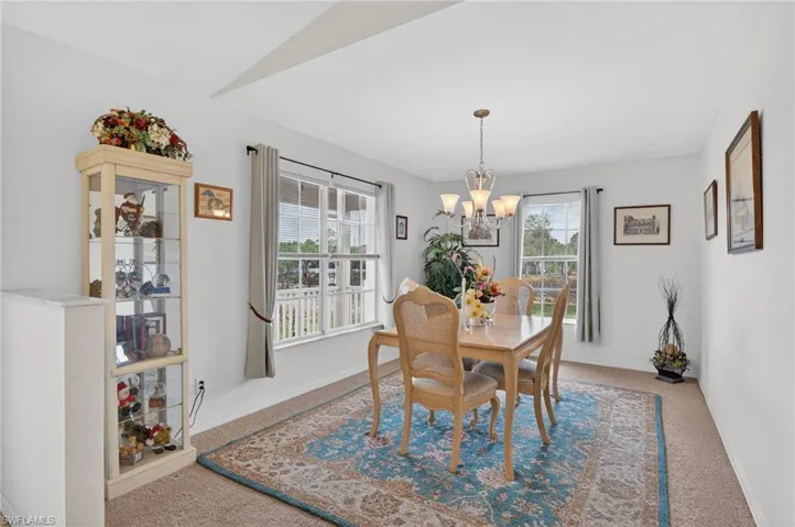 Carpeted dining room with baseboards and a chandelier