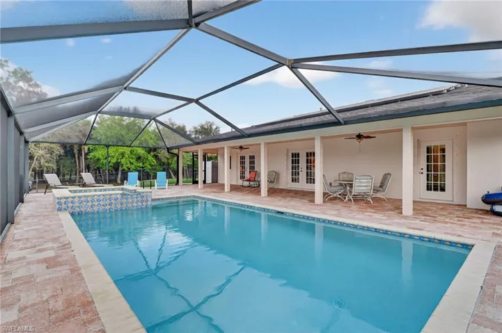 Integrated pool / hot tub with french doors, glass enclosure, a sunroom, and a patio