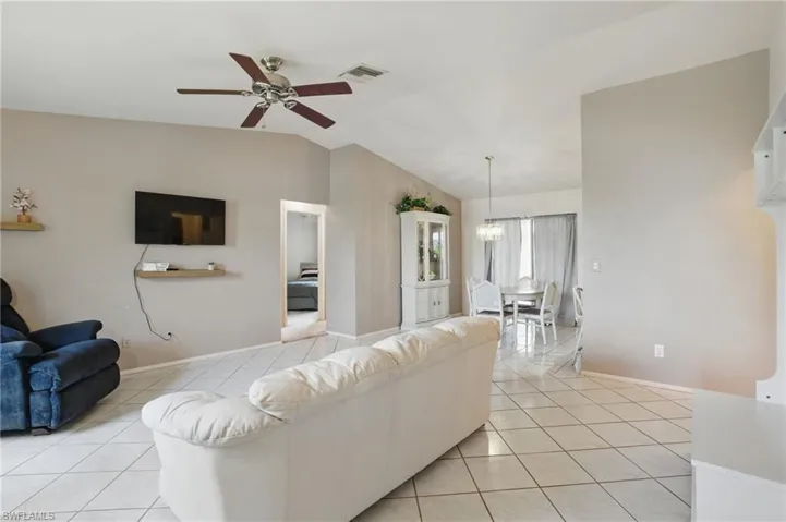 Living room with ceiling fan, light tile patterned floors, and natural light.