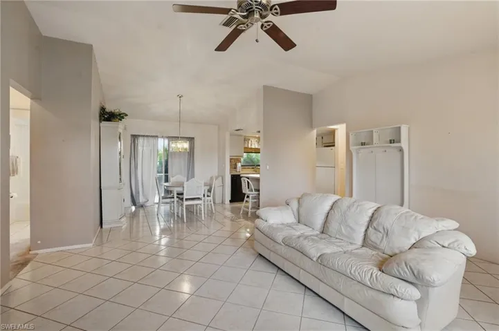 Living room with ceiling fan, light tile patterned floors, and natural light.