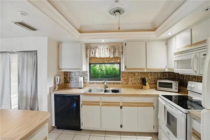 Kitchen featuring light tile floors, window above sink, and recessed lighting.