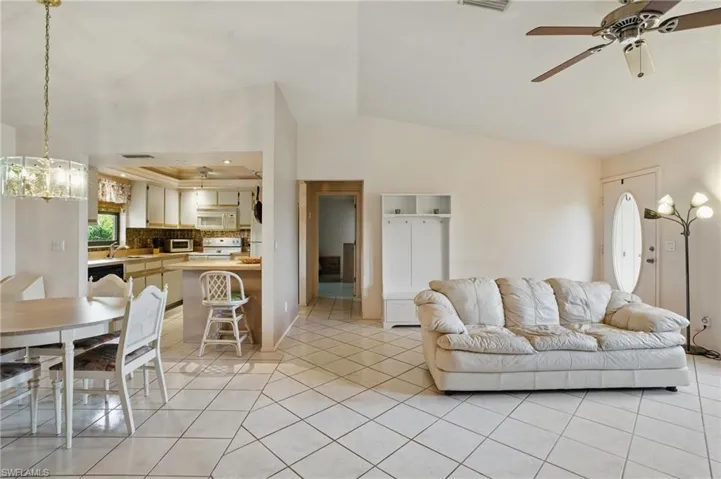 Living room with ceiling fan, light tile patterned floors, and natural light.