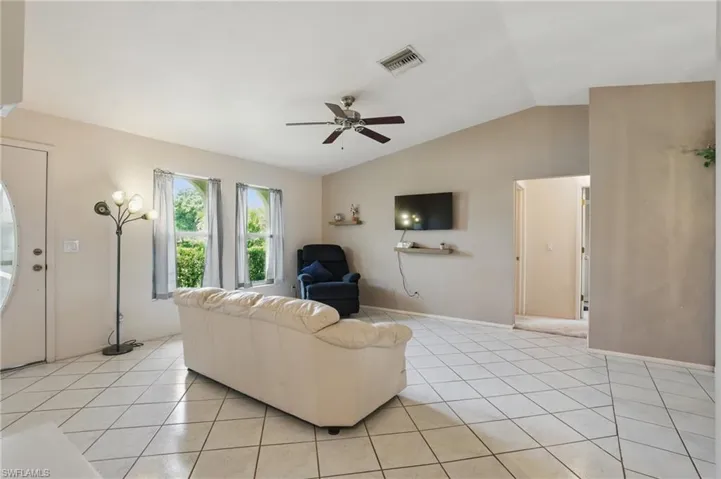 Living room with ceiling fan, light tile patterned floors, and natural light.