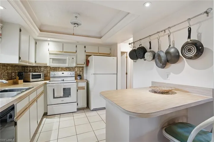 Kitchen featuring light tile floors, window above sink, and recessed lighting.