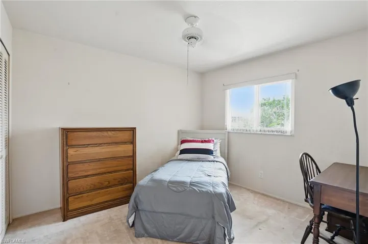 Carpeted guest bedroom with celling fan and closet.