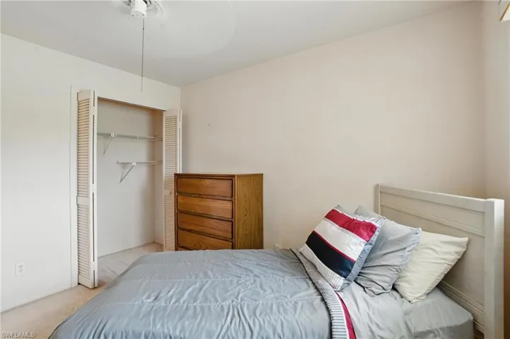 Carpeted guest bedroom with celling fan and closet.