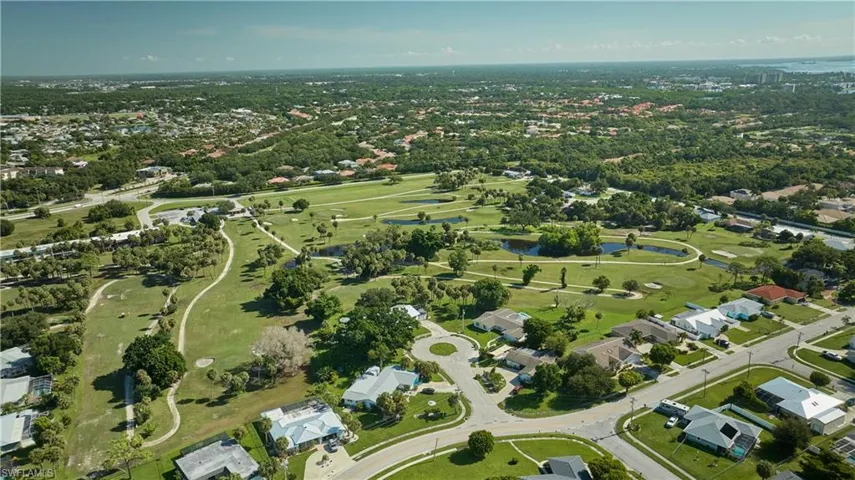 View of property location featuring nearby suburban area, a large body of water, and a golf club