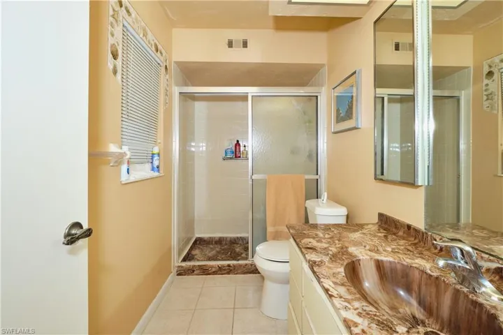 Bathroom featuring light tile patterned floors, vanity, and a shower stall