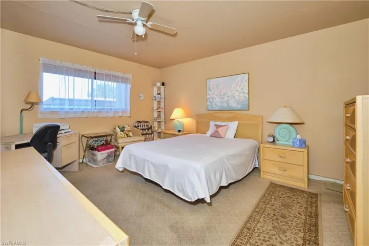 Carpeted bedroom with a ceiling fan and a desk