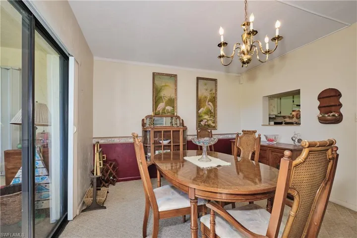 Dining room with crown molding, a chandelier, and light carpet
