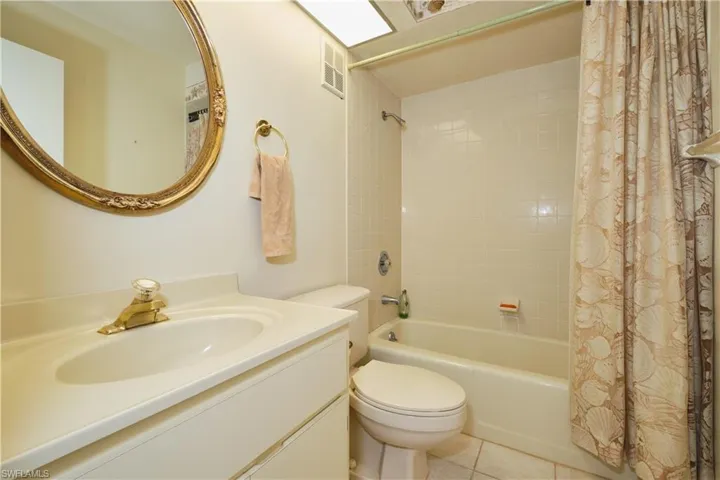 Bathroom featuring shower / bath combo with shower curtain, vanity, and light tile patterned flooring