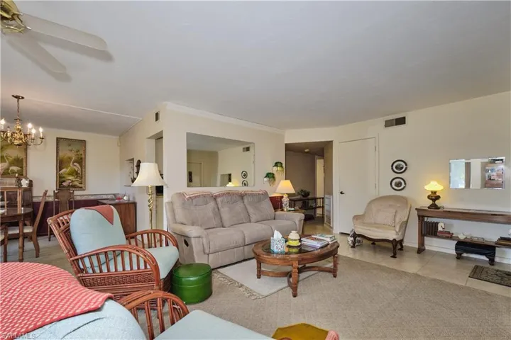 Tiled living room with a chandelier, a ceiling fan, and crown molding