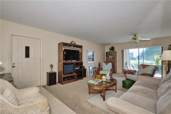 Living area with a ceiling fan, tile patterned flooring, and carpet