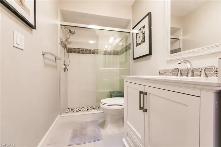 Bathroom with tile patterned flooring, vanity, a shower with shower door, and toilet