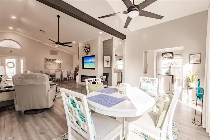 Dining area featuring beamed ceiling, ceiling fan with notable chandelier, light hardwood / wood-style floors, and high vaulted ceiling