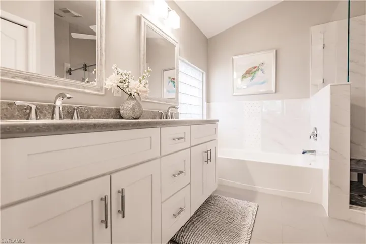 Bathroom featuring tile patterned floors, a bathing tub, vanity, and vaulted ceiling