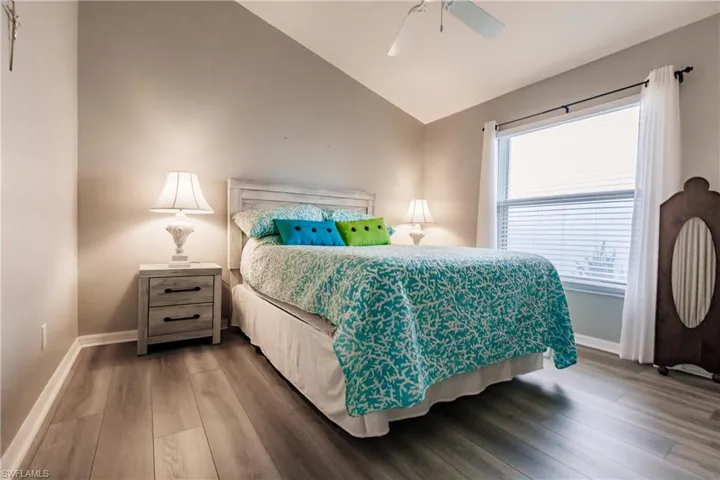 Bedroom featuring ceiling fan, wood-type flooring, and vaulted ceiling