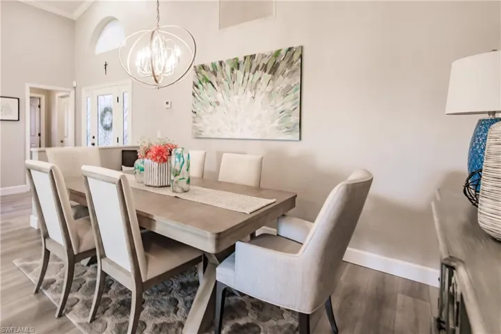 Dining area featuring a chandelier, hardwood / wood-style floors, a towering ceiling, and ornamental molding