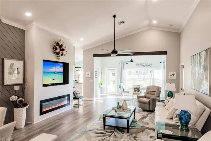 Living room featuring crown molding, hardwood / wood-style floors, ceiling fan, and vaulted ceiling