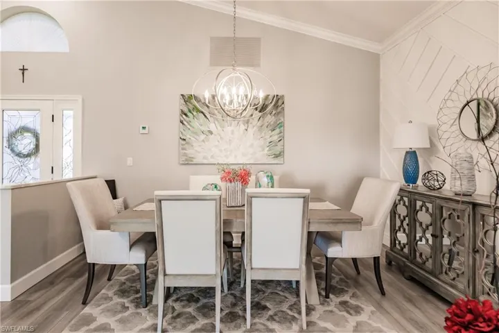 Dining room featuring hardwood / wood-style floors, a healthy amount of sunlight, ornamental molding, and a chandelier