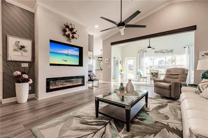 Living room with hardwood / wood-style floors, lofted ceiling, and ornamental molding