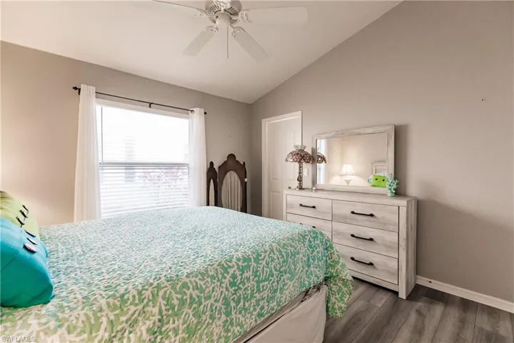 Bedroom featuring dark hardwood / wood-style flooring, vaulted ceiling, and ceiling fan