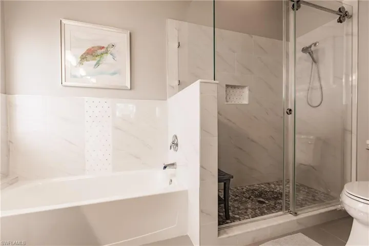 Bathroom with tile patterned flooring, separate shower and tub, and toilet