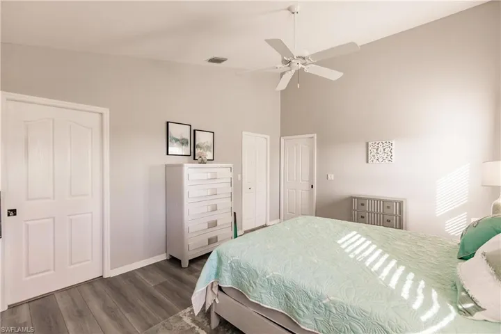 Bedroom featuring multiple closets, ceiling fan, and dark hardwood / wood-style floors