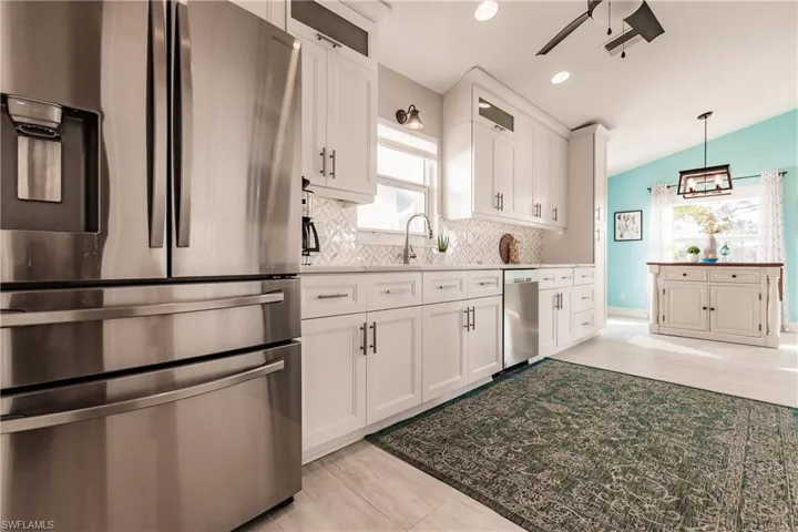 Kitchen with appliances with stainless steel finishes, backsplash, vaulted ceiling, ceiling fan, and white cabinets