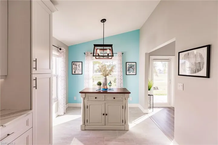 Hallway with light tile patterned flooring, vaulted ceiling, and an inviting chandelier