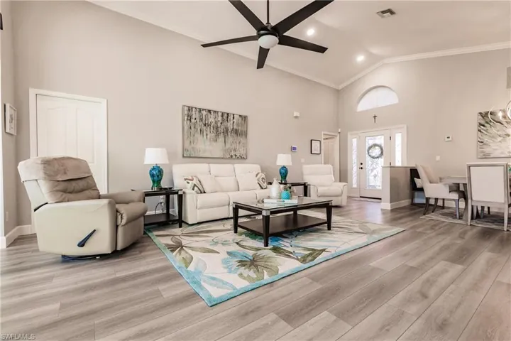 Living room with light hardwood / wood-style floors, high vaulted ceiling, ceiling fan, and crown molding