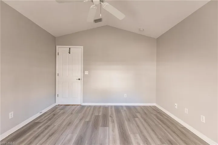 Unfurnished room with ceiling fan, vaulted ceiling, and light wood-type flooring