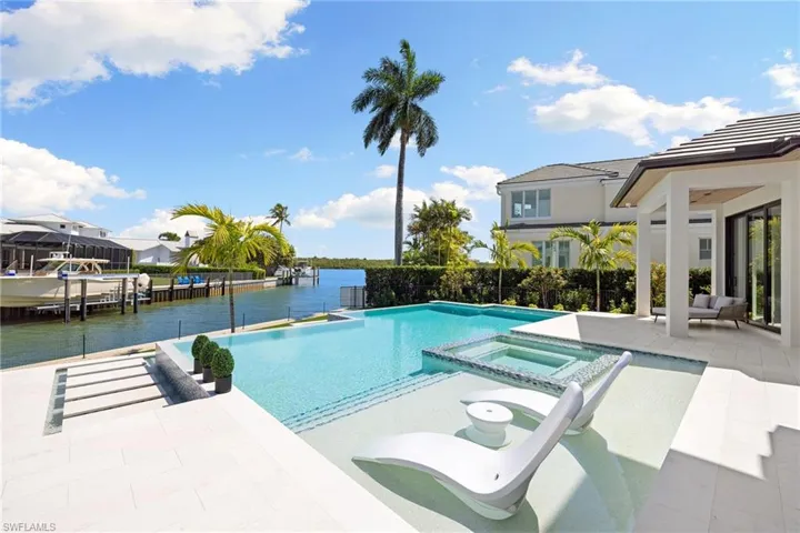 Integrated pool / spa featuring a patio, a water view, and a boat dock