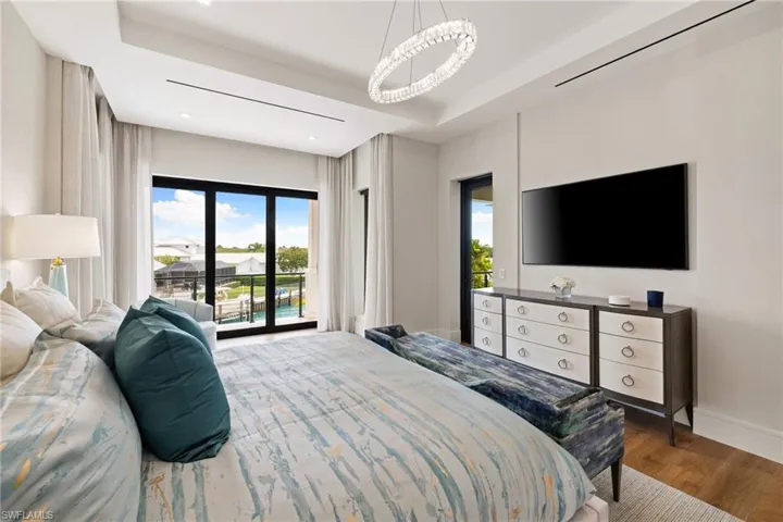 Bedroom featuring access to exterior, wood finished floors, and a raised ceiling