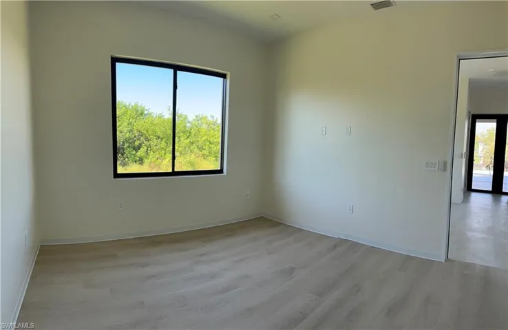 Light wood-finish flooring, a large window with black trim, and recessed ceiling lighting