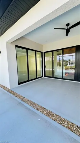 Expansive covered patio featuring large format tile flooring, black ceiling fan, and large sliding glass doors