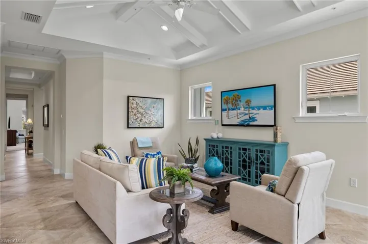 Tiled living room with ceiling fan, a wealth of natural light, and vaulted ceiling with beams